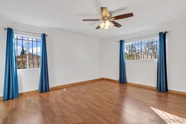 empty room with wood-type flooring, plenty of natural light, and ceiling fan