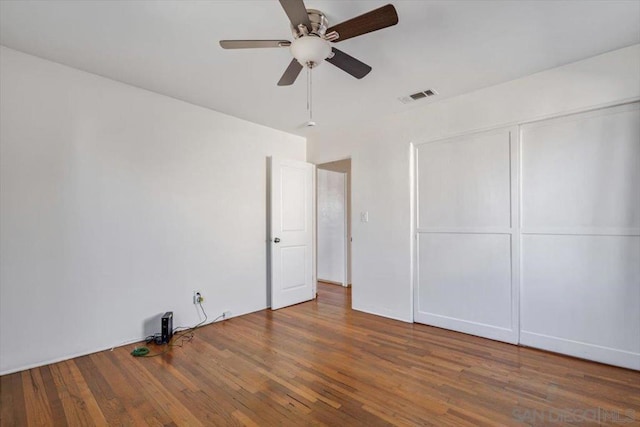 unfurnished bedroom with ceiling fan, wood-type flooring, and a closet