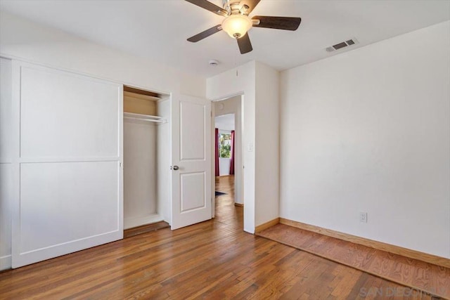 unfurnished bedroom with ceiling fan, a closet, and wood-type flooring