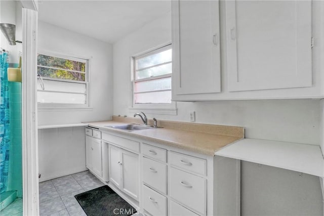 kitchen with light tile patterned flooring, white cabinetry, and sink