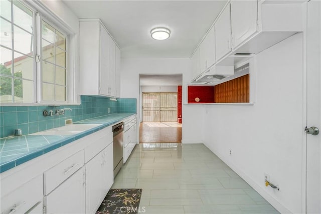 kitchen featuring dishwasher, tile countertops, white cabinetry, and sink