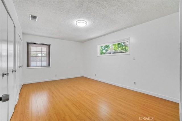 empty room featuring a textured ceiling and light hardwood / wood-style flooring