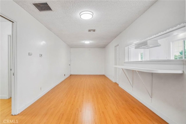 unfurnished room with hardwood / wood-style floors and a textured ceiling