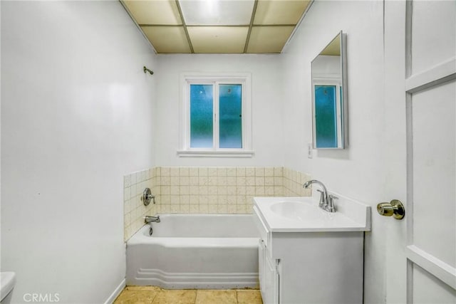 bathroom featuring tile patterned flooring, a bathtub, a drop ceiling, and vanity