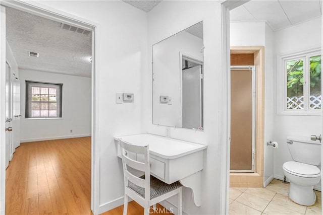 bathroom featuring hardwood / wood-style floors, a shower with door, a textured ceiling, and toilet