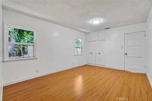 spare room with a textured ceiling and light wood-type flooring