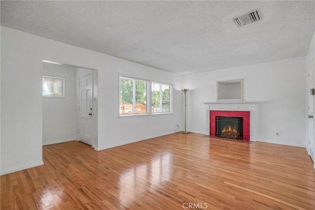 unfurnished living room with a fireplace, light wood-type flooring, and a textured ceiling