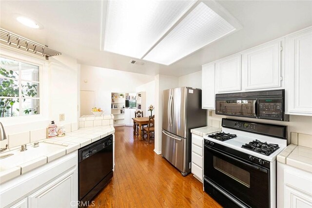 27551 Paseo Tamara, San Juan Capistrano, CA 92675 - kitchen featuring black appliances, tile countertops, light wood-style floors, white cabinets, and a sink