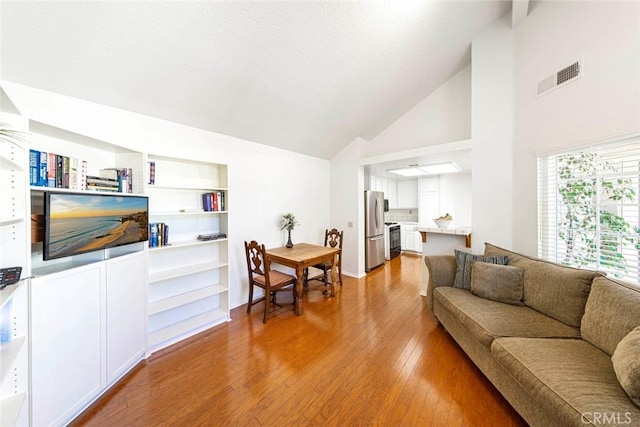 living room with light wood-type flooring and high vaulted ceiling