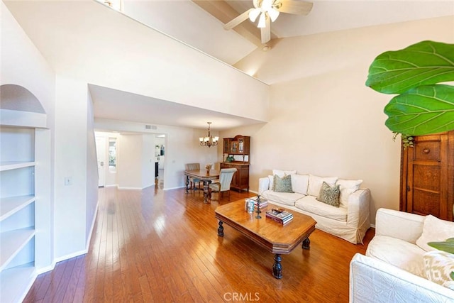 living room with ceiling fan with notable chandelier, hardwood / wood-style flooring, and lofted ceiling