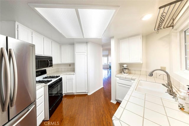 kitchen featuring stainless steel fridge, tile counters, white cabinets, and white range with gas stovetop