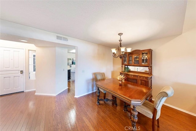 dining area with dark hardwood / wood-style flooring and an inviting chandelier