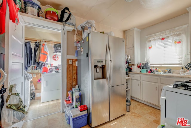 kitchen featuring white gas range, stainless steel fridge, washer / dryer, and white cabinetry