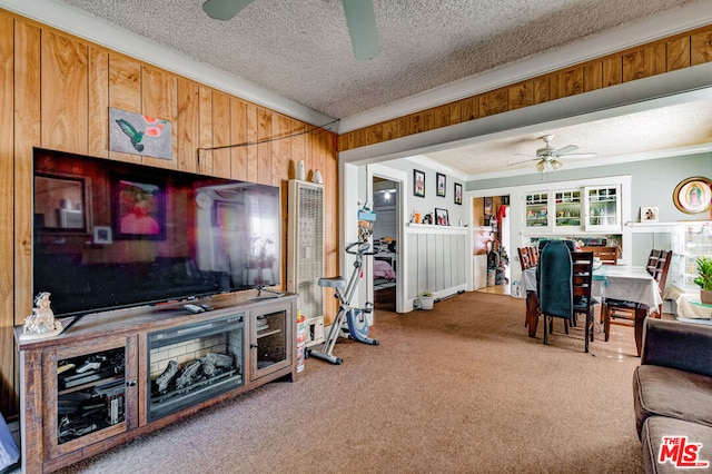 living room with carpet flooring, ceiling fan, ornamental molding, and a textured ceiling