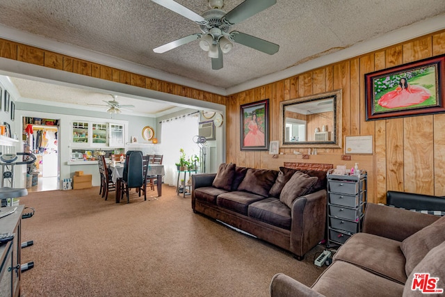 living room with carpet floors, wood walls, and ceiling fan