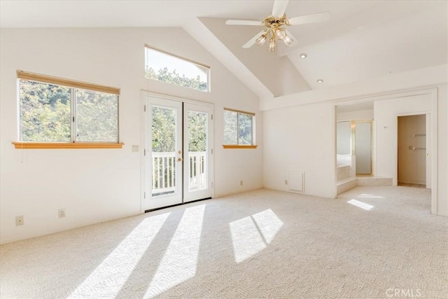 carpeted empty room featuring ceiling fan, high vaulted ceiling, and french doors