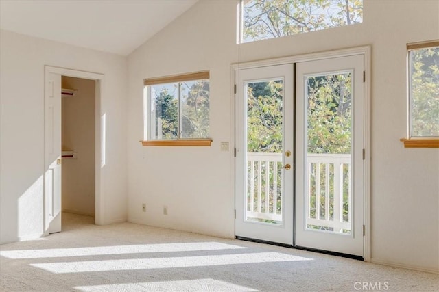 doorway to outside with light carpet, plenty of natural light, and vaulted ceiling