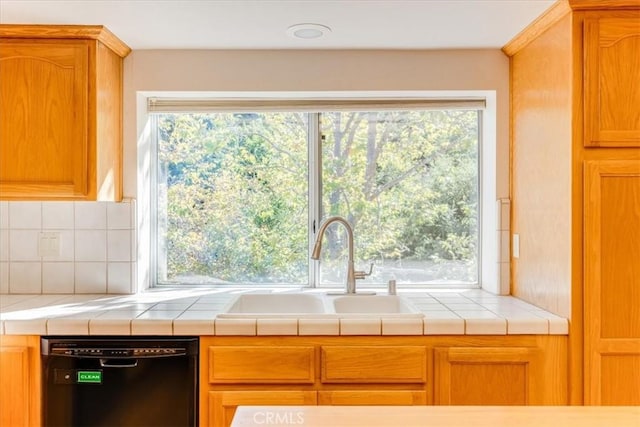 kitchen with decorative backsplash, tile counters, dishwasher, and sink