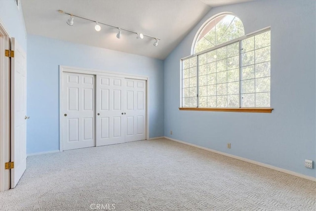 unfurnished bedroom featuring light carpet, a closet, and lofted ceiling