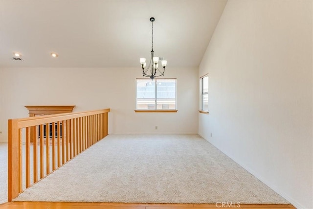 unfurnished room with lofted ceiling, carpet floors, and an inviting chandelier