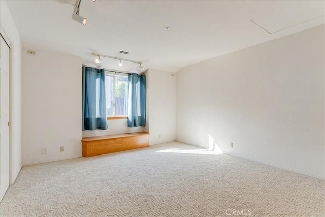 carpeted empty room featuring track lighting