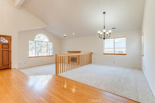 spare room with a wealth of natural light, a chandelier, and light wood-type flooring