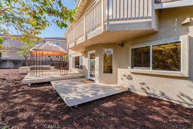 rear view of property featuring a gazebo and a balcony