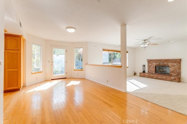 unfurnished living room with ceiling fan, light wood-type flooring, and a fireplace