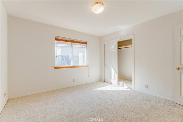 unfurnished bedroom with light colored carpet and a closet