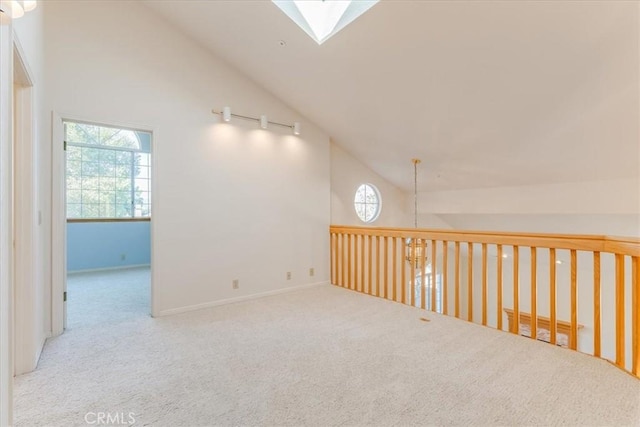 carpeted empty room featuring a skylight and high vaulted ceiling