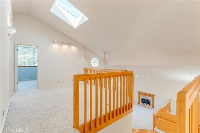 hallway with lofted ceiling with skylight and light carpet