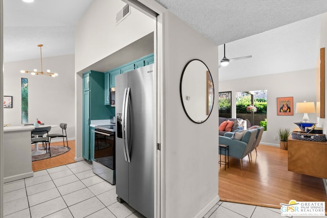 kitchen with ceiling fan with notable chandelier, light hardwood / wood-style floors, lofted ceiling, and appliances with stainless steel finishes