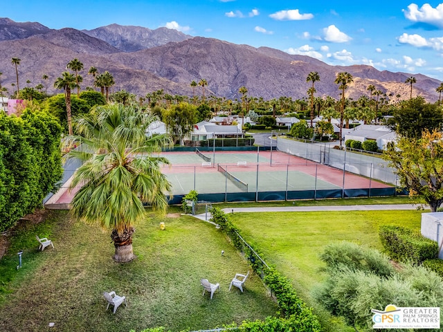 view of tennis court with a mountain view and a yard