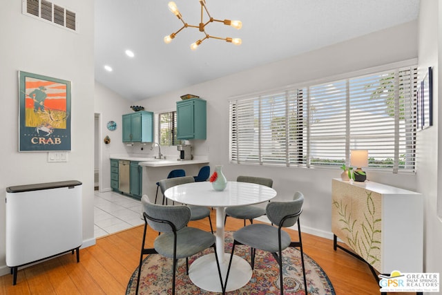 dining space featuring lofted ceiling, light wood-type flooring, sink, and a chandelier