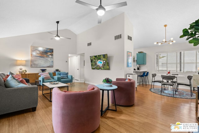 living room featuring high vaulted ceiling, light hardwood / wood-style floors, and ceiling fan with notable chandelier