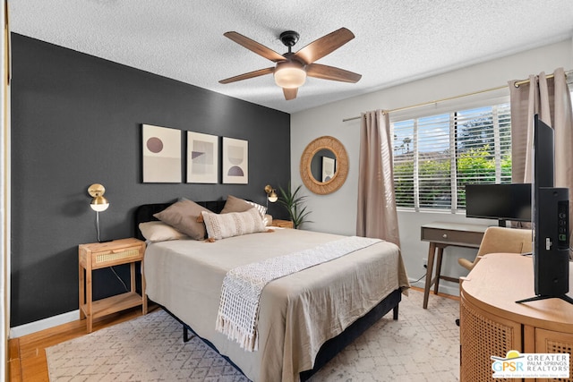 bedroom featuring ceiling fan, a textured ceiling, and light wood-type flooring