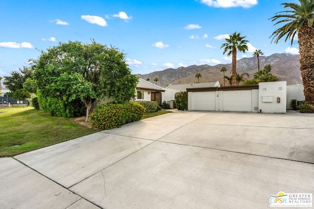 view of front of house featuring a mountain view, a front yard, and a garage