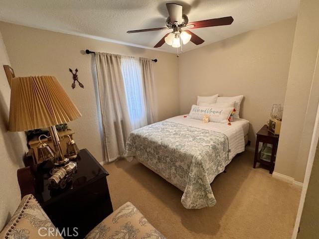 carpeted bedroom with ceiling fan and a textured ceiling