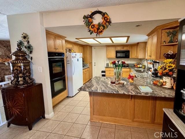 kitchen with sink, light tile patterned floors, black appliances, stone countertops, and kitchen peninsula