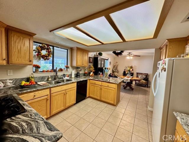 kitchen featuring light tile patterned flooring, black dishwasher, sink, white refrigerator, and kitchen peninsula