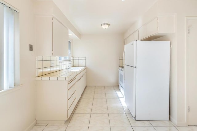 kitchen featuring sink, white appliances, tasteful backsplash, tile counters, and white cabinets