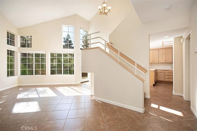 staircase featuring tile patterned floors, a notable chandelier, and high vaulted ceiling