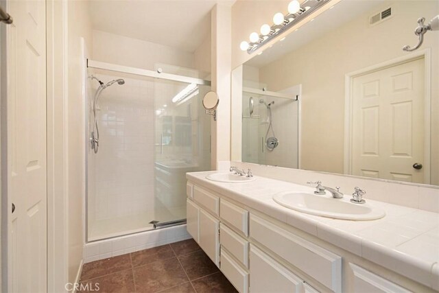 bathroom with tile patterned floors, a shower with door, and vanity