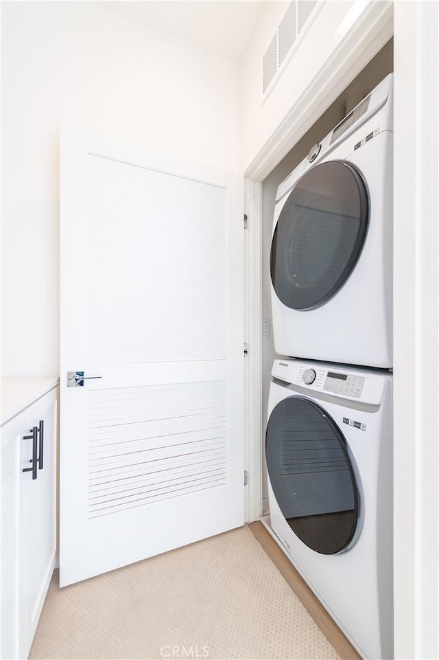 washroom with light carpet and stacked washer and clothes dryer