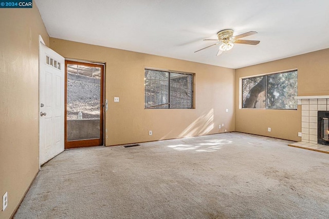 unfurnished living room with ceiling fan, light carpet, and a wealth of natural light