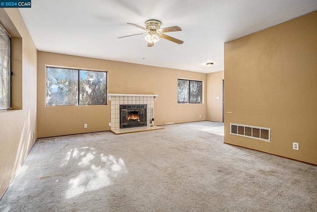 unfurnished living room featuring a tile fireplace, ceiling fan, and light carpet