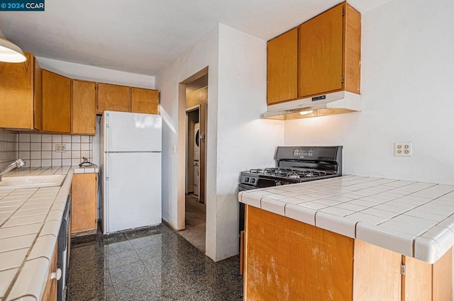 kitchen with tile counters, white fridge, black range with gas stovetop, and sink