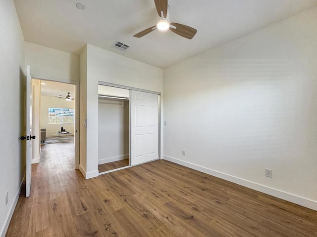 unfurnished bedroom featuring wood-type flooring, a closet, and ceiling fan