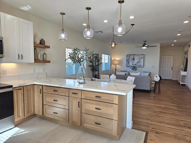 kitchen featuring ceiling fan, stainless steel appliances, kitchen peninsula, pendant lighting, and light wood-type flooring