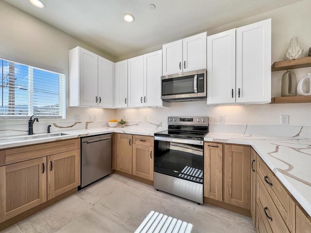 kitchen featuring white cabinets, appliances with stainless steel finishes, light stone countertops, and sink